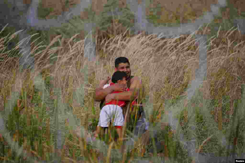 A migrant holds his child on the Serbian side of the fence in Asotthalom, Hungary. Hundreds of migrants spent the night in the open on Serbia's northern border with Hungary, their passage to western Europe stalled by a Hungarian crackdown to confront the continent's worst refugee crisis in two decades.