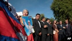 FILE - A supporter of the opposition Cambodia National Rescue Party holds a poster of the party leader Kem Sokha during a rally joined by lawmakers near an appeals court in Phnom Penh, Cambodia, Sept. 26, 2017. 
