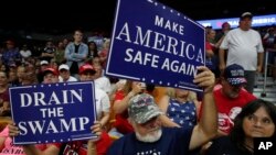 Para pendukung mengacungkan poster-poster berisi dukungan saat Presiden Donald Trump berbicara dalam sebuah rapat umum di Charleston, West Virginia, 21 Agustus 2018.
