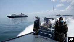 Panamanian Navy Police navigate near the anchored Zaandam cruise ship, carrying some guests with flu-like symptoms, after it arrived at the bay of Panama City, March 27, 2020, amid the worldwide spread of the new coronavirus. 