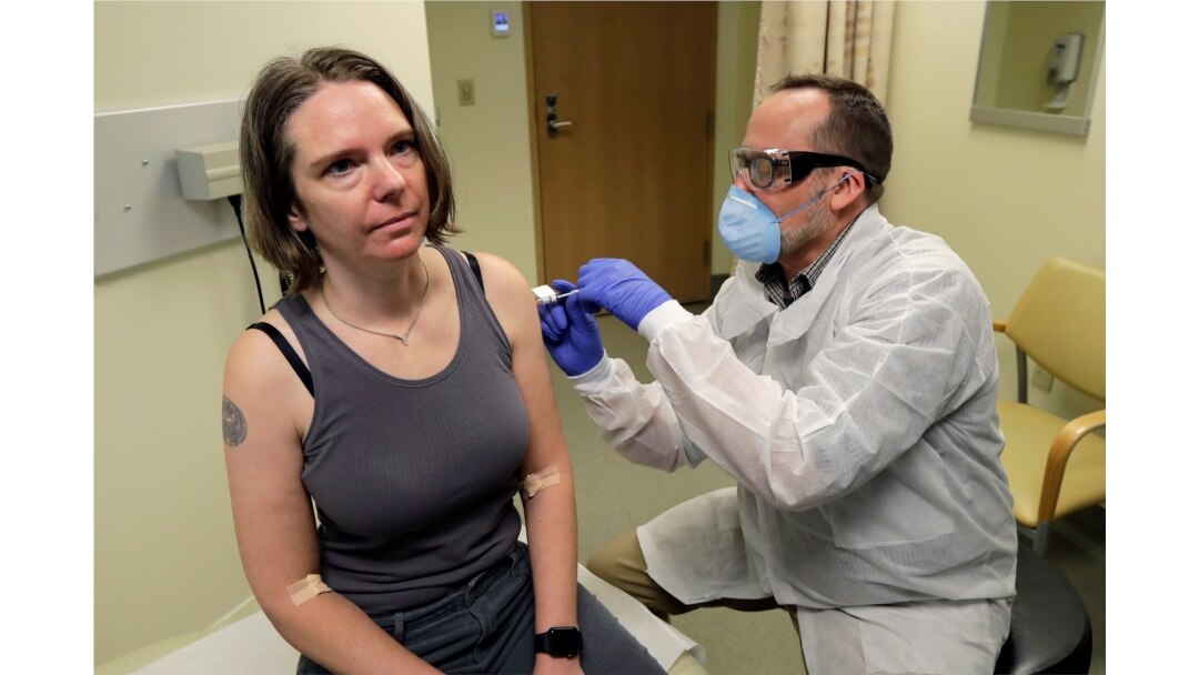 A pharmacist gives Jennifer Haller, left, the first shot in the first-stage safety study clinical trial of a potential vaccine for COVID-19 at the Kaiser Permanente Washington Health Research Institute in Seattle, Washington, March 16, 2020.