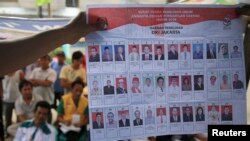 Warga menyaksikan petugas penghitungan suara saat memperlihatkan kertas-kertas suara di sebuah TPS di Jakarta (9/4).