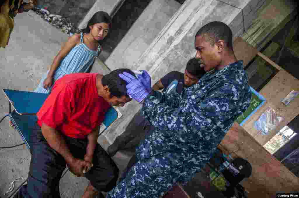 A U.S. Hospital Corpsman assists Philippine nurses in treating a patient's head wound at the Immaculate Conception School refugee camp. (U.S. Navy)