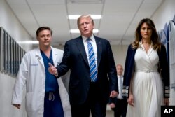 President Donald Trump, center, accompanied by first lady Melania Trump, right, and Dr. Igor Nichiporenko, left, speak to reporters while visiting with medical staff and victims of a mass shooting at a local school in Pompano Beach, Fla., Feb. 16, 2018.