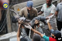 Sept. 27, 2016 photo, provided by the Syrian Civil Defense group known as the White Helmets, shows a Civil Defense worker carrying the body of a child after airstrikes hit al-Shaar neighborhood in Aleppo, Syria.