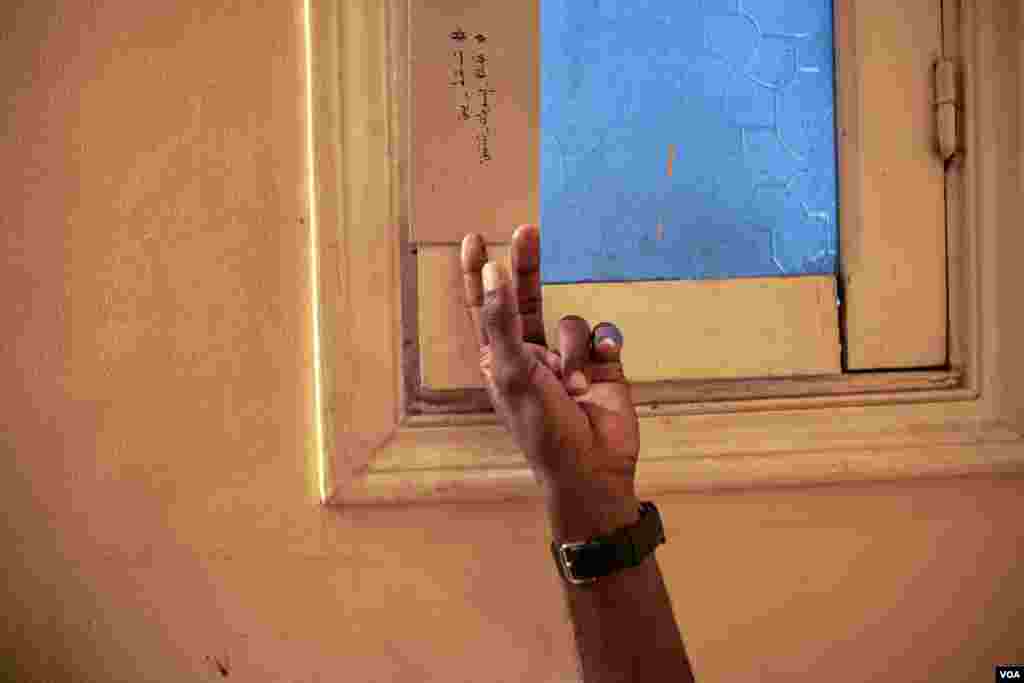 A sign hangs on a window inside the Cairo house of Sudanese refugees with trending revolutionary hashtags that say in Arabic "Only step down, cities of Sudan revolts." (H. Elrasam/VOA)