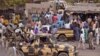 Nigerian soldiers, left, pass on the back of a armed truck as they patrol at a local market Tuesday, Jan. 27, 2015, after recent violence in surrounding areas at Maiduguri, Nigeria. Islamic extremists are rampaging through villages in northeast Nigeria’s Adamawa state, killing, burning and looting with no troops deployed to protect civilians, fleeing villagers said. Government officials say national security is one reason for delays in issuing visas to journalists. (AP Photo/Jossy Ola)
