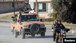 Rebeldes liderados pelo grupo militante islâmico Hayat Tahrir al-Sham conduzem uma mota em al-Rashideen, província de Alepo, Síria, a 29 de novembro de 2024.