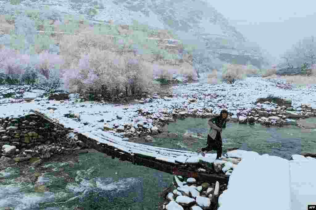 An Afghan boy walks across a footbridge during the first snowfall in the Dara district of Afghanistan's Panjshir province.