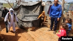 Petugas kesehatan menyemprotkan disinfektan untuk mencegah perebakan Covid-19 di kamp pengungsi Suriah di Marjayoun, Lebanon. 