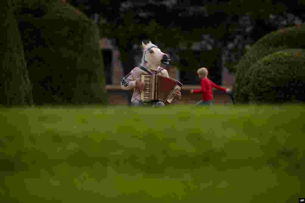 A child runs by a person wearing a horse mask and playing an accordion in the Maria Theresien Platz in Vienna, Austria, Sept. 28, 2024.