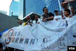 國民教育家長關注組成員展示一幅大橫額，諷刺當局推行國民教育毒害香港學童