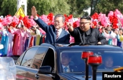 문재인 한국 대통령과 김정은 북한 국무위원장이 18일 차량에 올라타 평양 시민들을 향해 손을 흔들어 보이고 있다. 평양사진공동취재단.