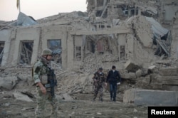 FILE - Afghan security forces and NATO troops investigate at the site of explosion near the German consulate office in Mazar-i-Sharif, Afghanistan, Nov. 11, 2016.