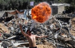 Anggota tim olahraga Bar Woolf Gaza tampil dengan api di atas reruntuhan bangunan yang hancur akibat serangan udara Israel baru-baru ini, di Beit Lahia, pada 26 Mei 2021. (Foto: AFP)
