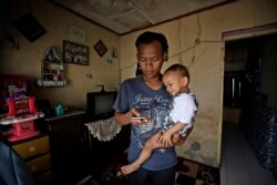 Budi Santosa, kehilangan pekerjaan sebagai koki di restoran China akibat pandemi, bersama anaknya di rumah kontrakan di Jakarta. (AP/Dita Alangkara).