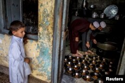 A boy stands while Pakistani religious students prepare food for their schoolmates at Darul Uloom Haqqania, an Islamic seminary and alma mater of several Taliban leaders, in Akora Khattak, Khyber Pakhtunkhwa province, Sept. 14, 2013.