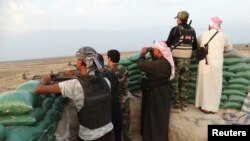 Tribal fighters carry their weapons as they take part in an intensive security deployment against Islamic State militants in the town of Amriyat al-Falluja,in Anbar province, Oct. 31, 2014. 