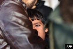 Seorang pria menenangkan seorang anak ketika orang-orang berduka atas kematian anggota keluara Akasha yang tewas akibt serangan Israel di kawasan Sheikh Adwan, di utara Kota Gaza, di Rumah Sakit Al-Maamadani, Sabtu, 30 November 2024. (Foto: Omar Al-Qattaa/AFP)