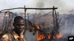 A policeman walks past the smoldering remains of a market in Rubkona near Bentiu in South Sudan, April 23, 2012.