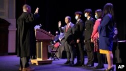 In this photo provided by Peg Shanahan, Lowell District Court Judge Stephen Geary, left, swears in new Mayor Sokhary Chau during the Lowell City Council swearing-in ceremony, Monday, Jan. 3, 2022, in Lowell, Mass., as Chau's family stands with him. 