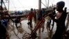 Migrant workers unload frozen fish from a boat at a fish market in Samut Sakhon Province, west of Bangkok, Friday, June 20, 2014. The United States had blacklisted Thailand and Malaysia for failing to meet its minimum standards in fighting human trafficking, a move that could strain relations with two important U.S. partners in Asia. Thailand had mounted a determined campaign to prevent a downgrade that could exact a cost toits lucrative seafood and shrimp industries for which America is a key market. (AP Photo/Sakchai Lalit)