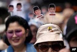 Pendukung mengenakan hiasan kepala bergambar calon presiden Prabowo Subianto dan pasangannya Gibran Rakabuming Raka, putra sulung Presiden Joko Widodo di Jakarta, 25 Agustus 2023. (Foto: AP)