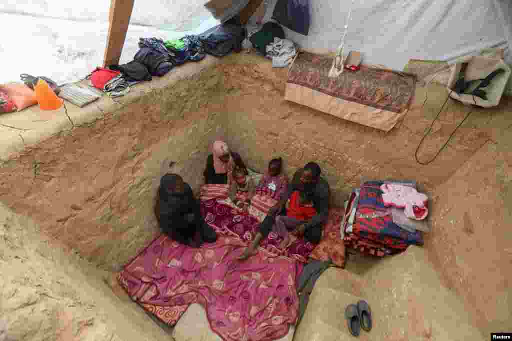 Displaced Palestinian man Tayseer Obaid sits with his family in an underground pit he dug at their tent encampment to protect them from Israeli strikes, in Deir Al-Balah, central Gaza Strip, Jan. 6, 2025.