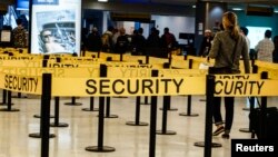 Para penumpang sedang berjalan menuju pemeriksaan keamanan di Bandara Internasional JFK di New York.