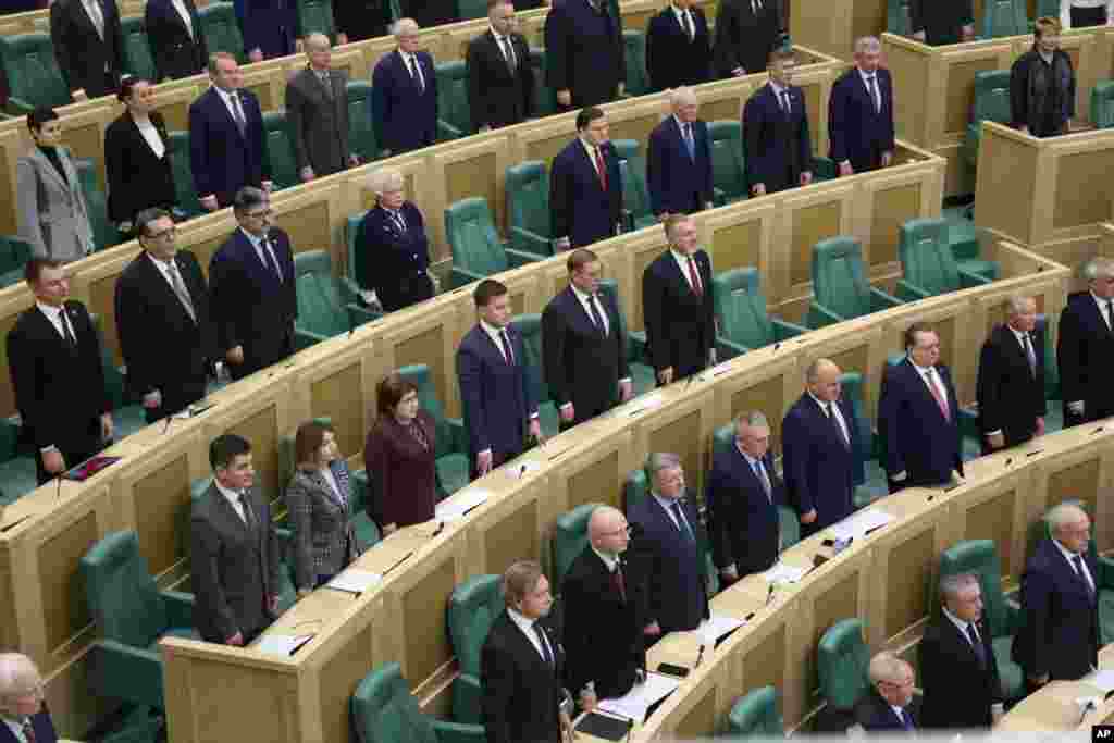 In this photo provided by the Federation Council of the Federal Assembly of the Russian Federation, lawmakers listen to the national anthem as they attend a session in Moscow. Lawmakers gave President Vladimir Putin permission to use military force outside the country.