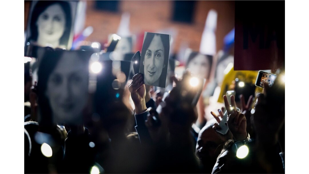 FILE - People hold pictures of journalist Daphne Caruana Galizia, who was slain in October 2017, as they protest in Valletta, Malta, Nov. 29, 2019.