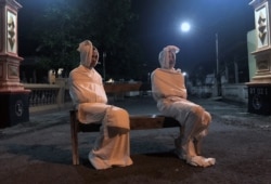 Para relawan mengenakan kostum 'pocong' agar warga mematuhi aturan tinggal di rumah untuk mencegah penularan virus corona di Desa Kepuh, Sukoharjo, Jawa Tengah, 1 April 2020. (Foto: Reuters)