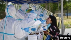 Seorang petugas kesehatan sedang melakukan tes usap pada seorang warga menyusul wabah virus corona (Covid-19) yang merebak kembali di Beijing, China, 20 Juni 2020.