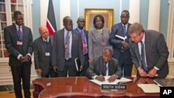 South Sudan's Minister of Finance and Economic Planning Kosti Manibe Ngai (L) signs the treaty to become IMF's newest member as US State Department Treaty Analyst Francis Holleran (R) looks on at the State Department, April 18, 2012 in Washington.

