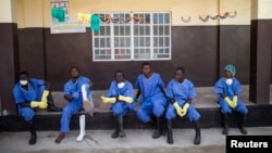 FILE - Health workers rest outside a quarantine zone at a Red Cross facility in the town of Koidu, Kono district in Eastern Sierra Leone, Dec. 19, 2014.