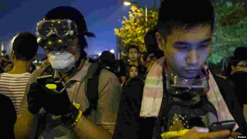 Protesters look their phones as they block the entrance to the offices of Hong Kong's Chief Executive Leung Chun-ying in Hong Kong, Oct. 2, 2014.