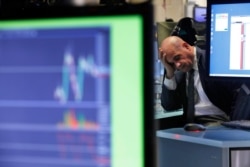 A specialist rests his head in his hand as he works on the floor of the New York Stock Exchange, Feb. 25, 2020. U.S. stocks fell a day after the market's biggest drop in two years.