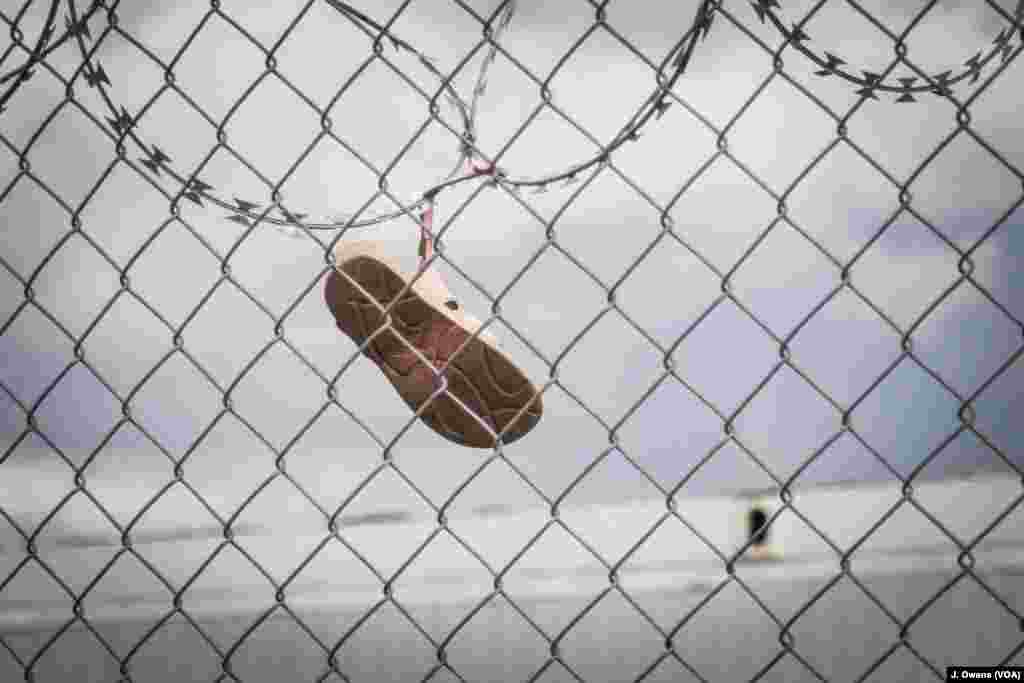 A child’s shoe hangs from the barb-wire lined fence at Vial camp on the Greek island of Chios.