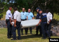 Polisi Perancis membawa sebuah potongan pesawat yang ditemukan di pantai Saint-Andre di Pulau Reunion (29/7).