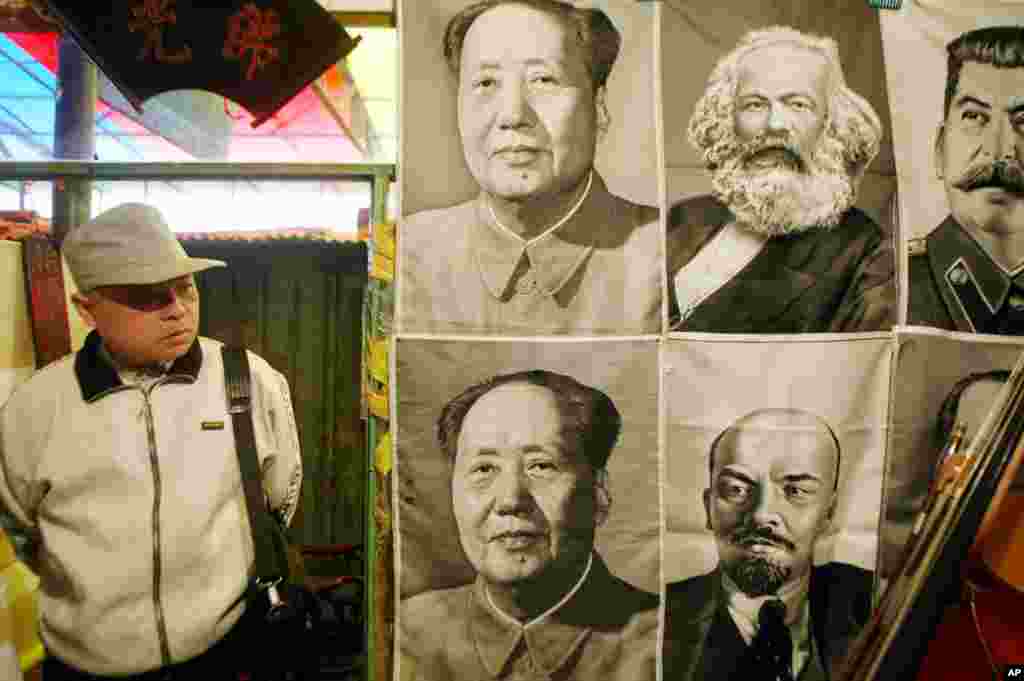 2002年10月26日,在北京的一个市场上,一名男子看着中国共产党领袖毛泽东,苏联领袖弗拉基米尔·列宁和约瑟夫·斯大林,以及社会主义理论家卡尔·马克思的肖像。