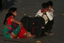A migrant worker carries a child on his shoulders as his family waits for transportation to their village in New Delhi, India, March 28, 2020.