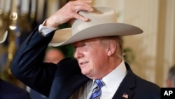 President Donald Trump tries on a Stetson hat during a "Made in America," product showcase featuring items created in each of the U.S. 50 states, at the White House, July 17, 2017.