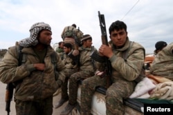 Kurdish People's Protection Units (YPG) fighters carry their weapons while riding on the back of a pick-up truck in Qamishli, Syria, March 11, 2016.
