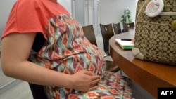 FILE - A pregnant woman works at her office in Tokyo on July 2, 2013.