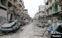 FILE - Damaged cars and buildings are seen in eastern Ghouta, Damascus, Syria, Feb. 25, 2018.