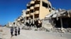 FILE - Youths walk past buildings that were destroyed during clashes between Libyan forces and Islamic State militants in Sirte, Libya, Nov. 1, 2017.