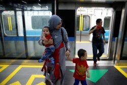 Seorang perempuan bersama anak-anaknya tiba di di sebuah stasiun saat uji coba Moda Raya Terpadu (MRT) di Jakarta, 12 Maret 2019.