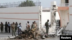 Somali government forces assess the scene of a suicide car explosion in front of the SYL hotel in the capital Mogadishu, Jan. 22, 2015. 