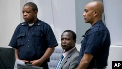 Dominic Ongwen, center, a senior commander in the Lord's Resistance Army, whose fugitive leader Kony is one of the world's most-wanted war crimes suspects, sits in the court room of the International Court in The Hague, Netherlands, Tuesday, Dec. 6, 2016.