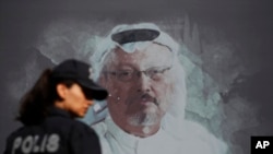 FILE - A Turkish police officer walks past a picture of slain Saudi journalist Jamal Khashoggi near the Saudi Arabia consulate in Istanbul, Oct. 2, 2019.